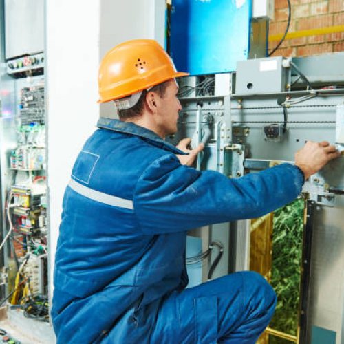 electrician worker adjusting equipment in elevator lift